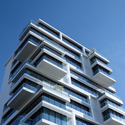 Striking low-angle shot of a modern condominium with unique balcony design and clear blue sky.